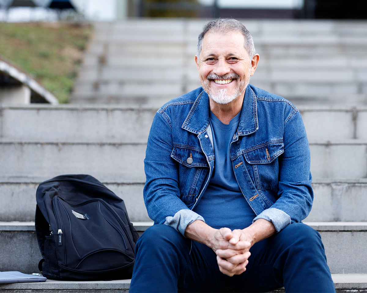 Smiling man sitting on the steps with a backpack