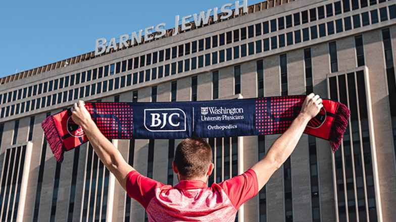 Man holding scarf with BJC logo on it