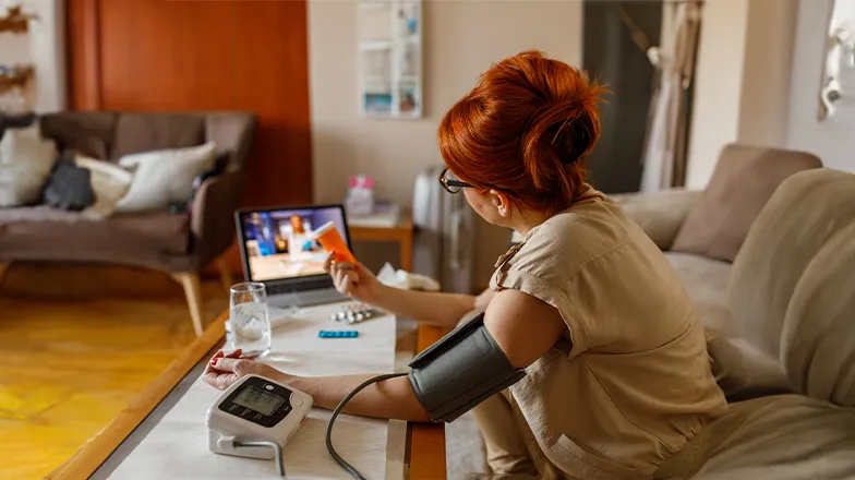Woman with blood pressure cuff on talking to a doctor virtually