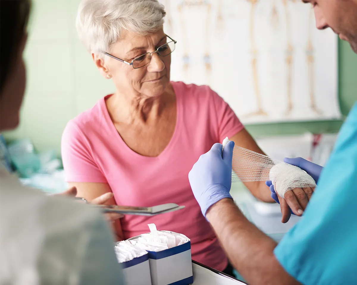 Older woman getting her hand bandaged by a doctor