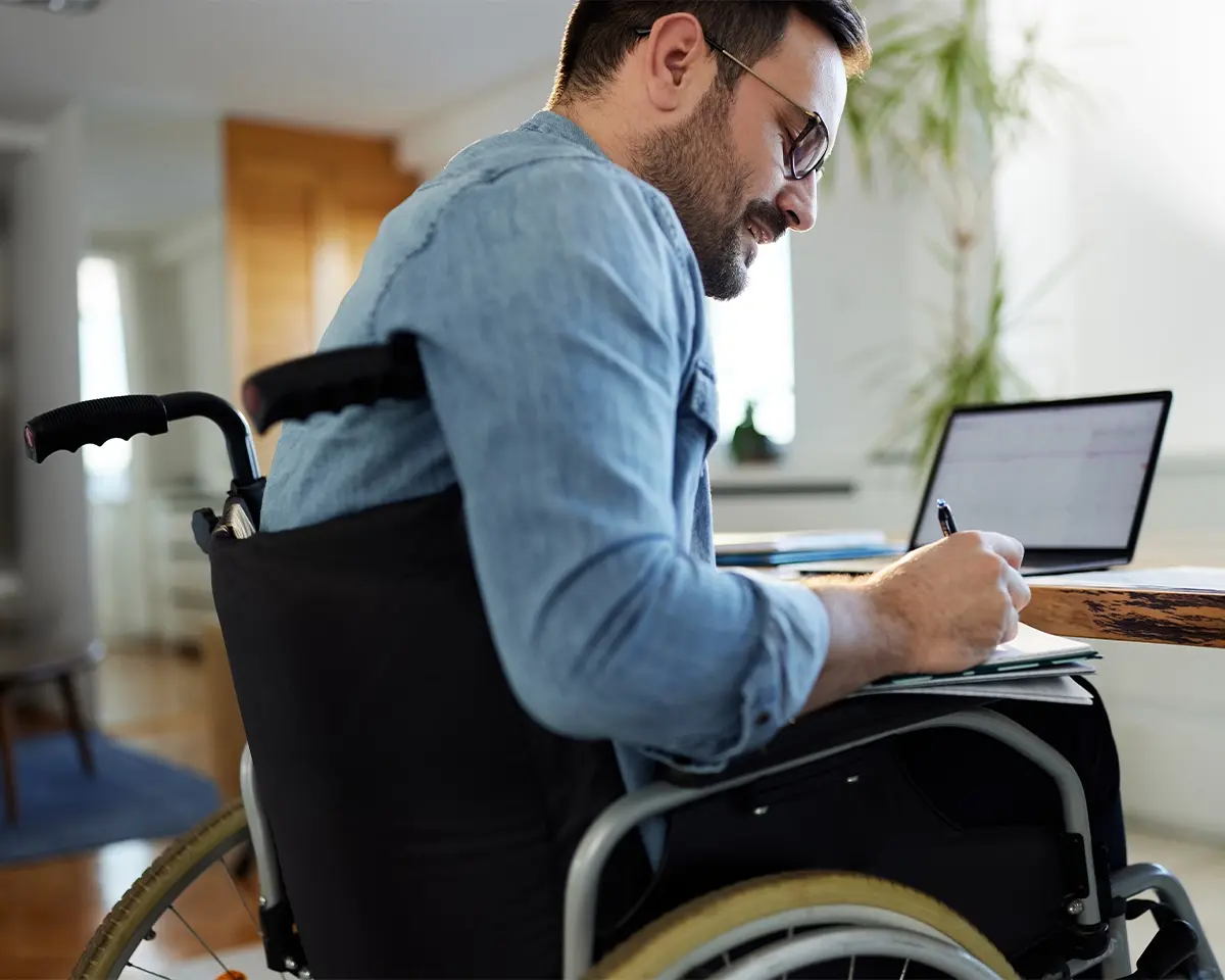 Man in wheel chair writing on a notepad