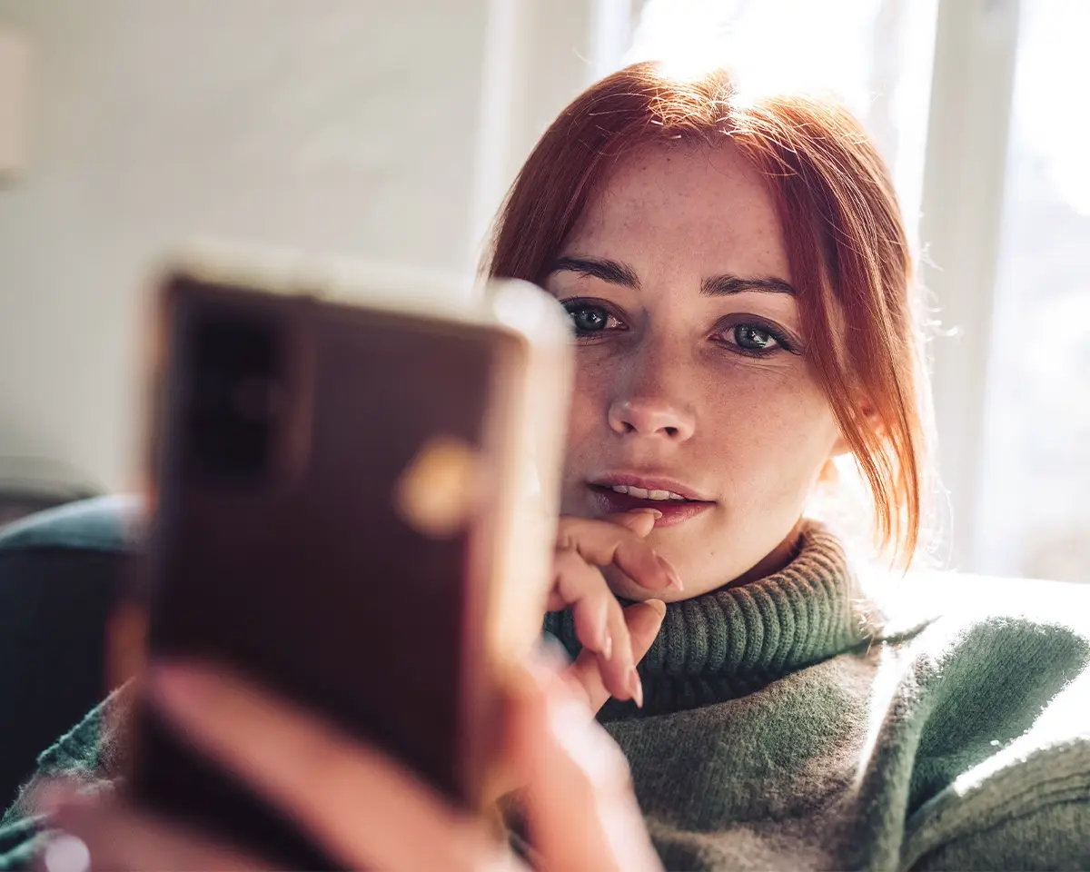 Woman looking pensive while holding up her phone