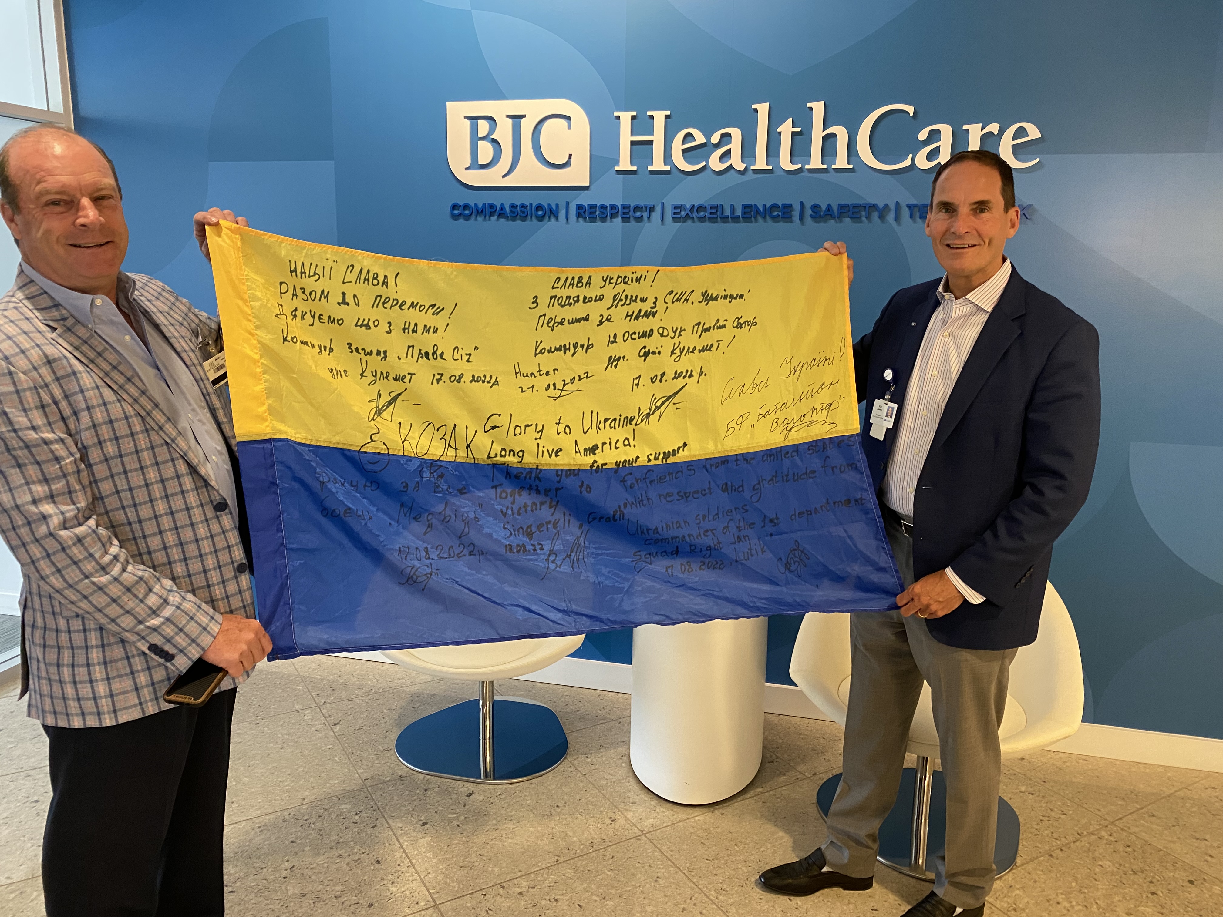 BJC Clinical Asset Management vice president Larry McWhirter, left, and BJC president and CEO Rich Liekweg hold a flag sent by Ukrainian soldiers